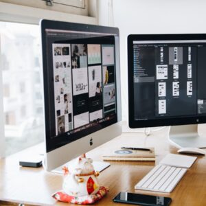 A sleek modern office setup featuring dual monitors, Apple devices, and creative decor in an indoor workspace.