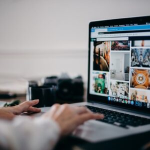 Close-up of hands using laptop for image searching and browsing digital photo gallery.