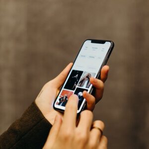Close-up of hands using a smartphone to browse a photo gallery app, showcasing modern technology.